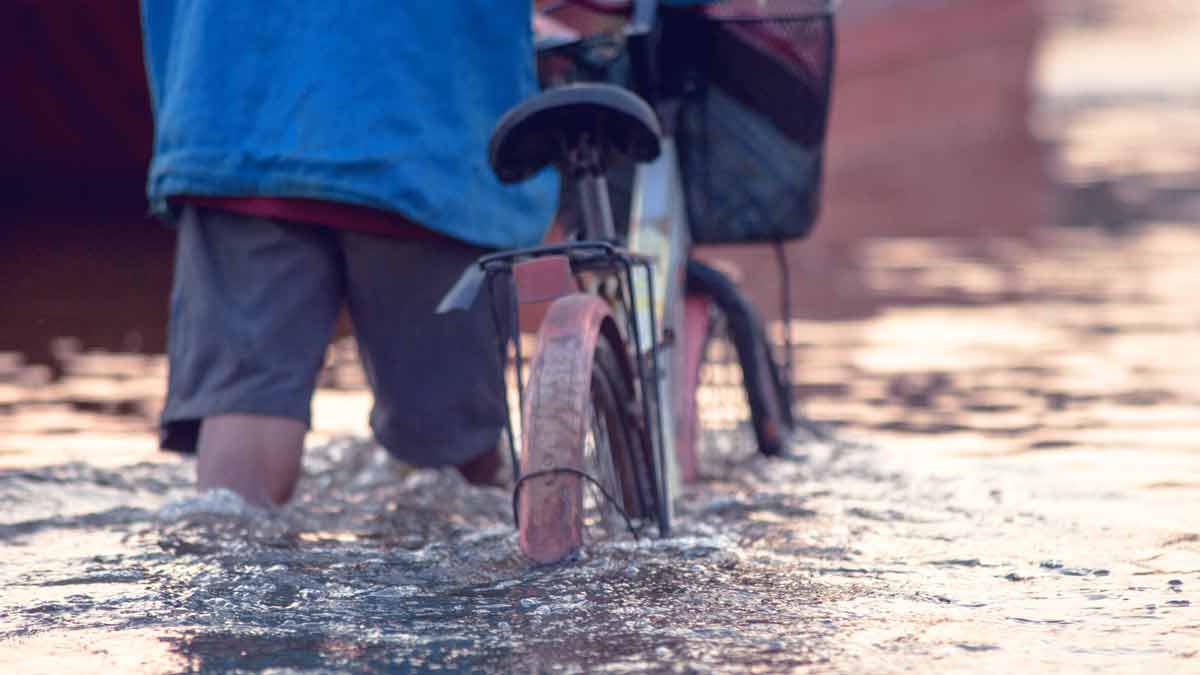 Ein Bewohner schiebt sein Fahrrad durch die Fluten. Auch Arztpraxen waren vom Hochwasser stark betroffen - doch es gibt eine Lösung.. 